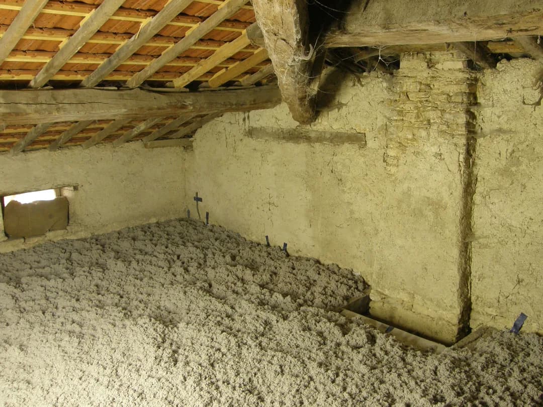 Loose-fill cellulose insulation blown across the floor of an older attic