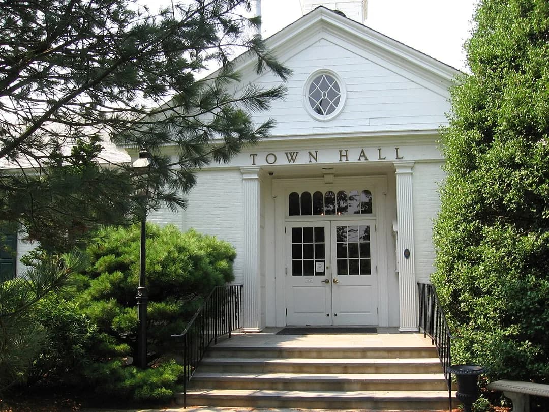 The white colonial Weston Town Hall framed by trees in Weston, Connecticut
